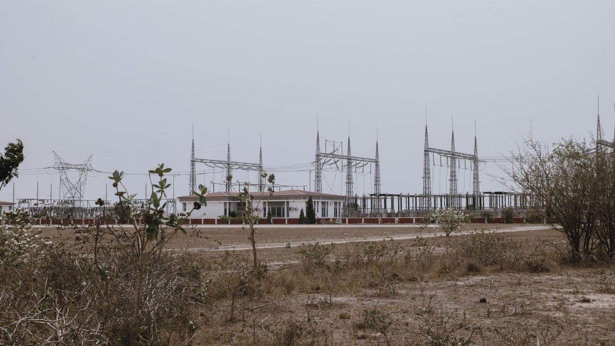 A barren landscape featuring an industrial power plant with transmission towers under cloudy skies.