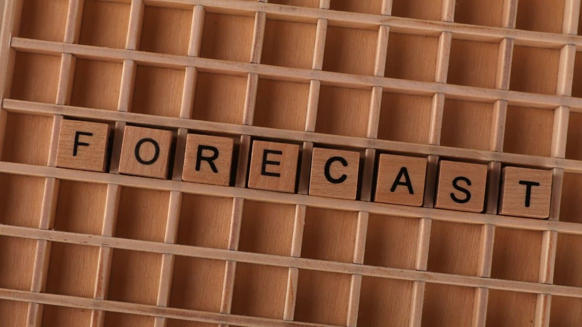 Scrabble-like wooden blocks spelling the word 'forecast' on a wooden grid surface.