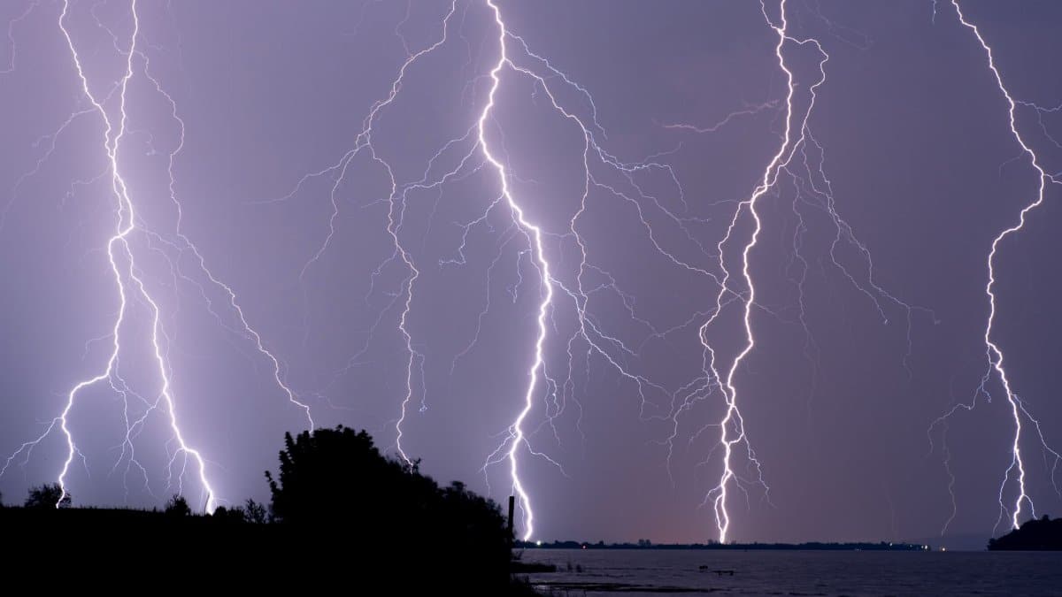 Lightning strikes over the ocean showcasing a dramatic thunderstorm during the night. Captured in high contrast.