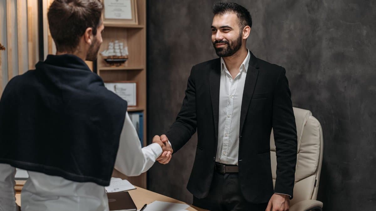 Two businessmen shaking hands in a modern office, sealing a business deal.
