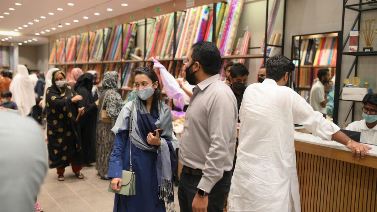 A bustling indoor fabric store with people shopping and browsing fabrics.