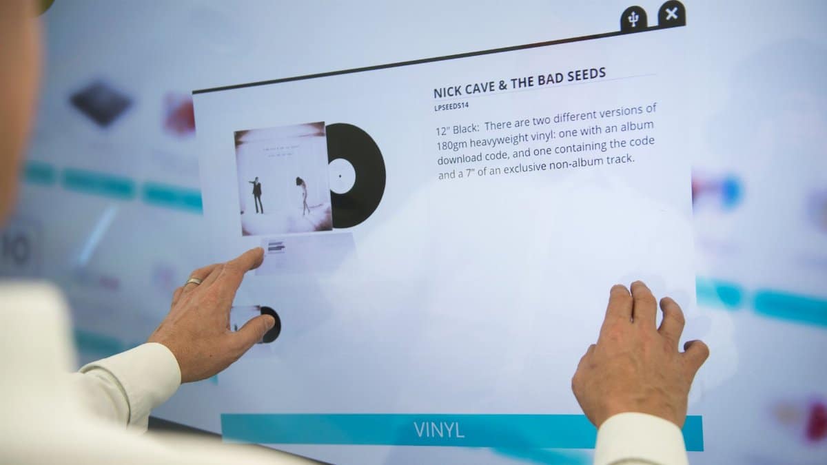 A person using a touchscreen to browse vinyl record information for Nick Cave & The Bad Seeds.