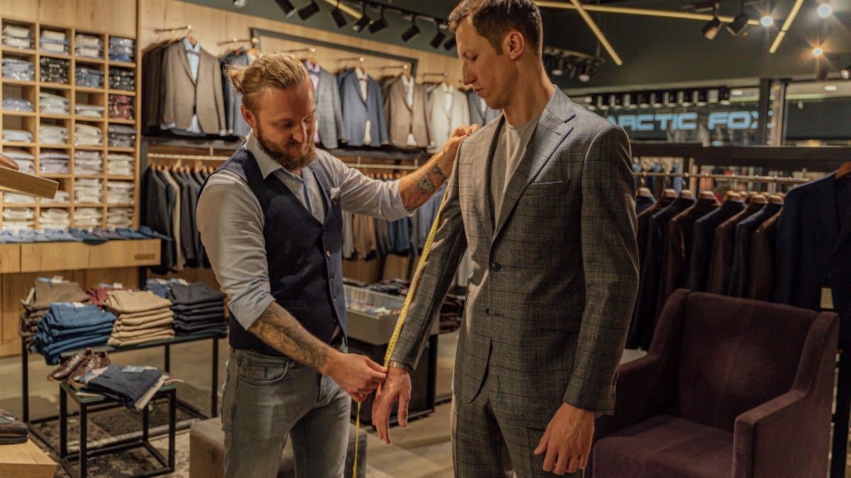 Tailor measuring a customer in a suit store for a perfect fit.