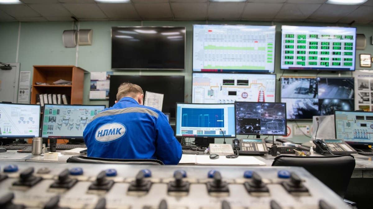An engineer monitors multiple screens in an industrial control room, ensuring smooth operations.