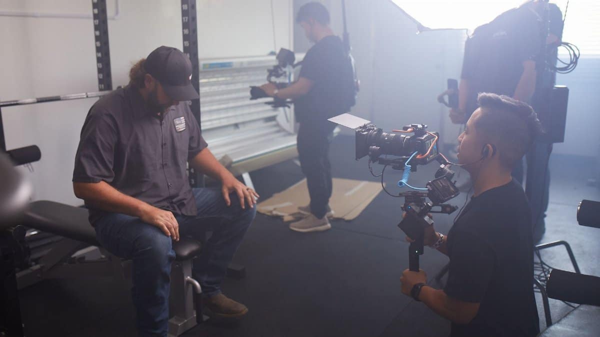 Behind-the-scenes of a video production session with crew and equipment in a modern studio setting.