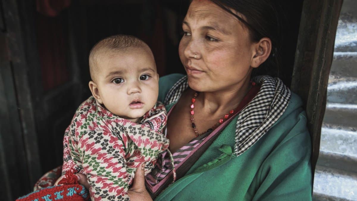 A mother holds her baby lovingly, showcasing cultural attire and family bond.