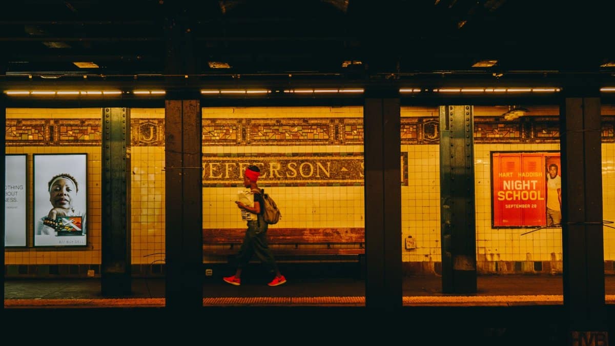 A person wearing bright sneakers walks through Jefferson subway station, capturing urban life in New York City.