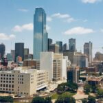 Aerial view of Dallas skyline featuring modern skyscrapers under a clear blue sky.