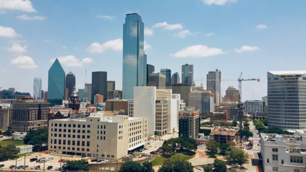 Aerial view of Dallas skyline featuring modern skyscrapers under a clear blue sky.