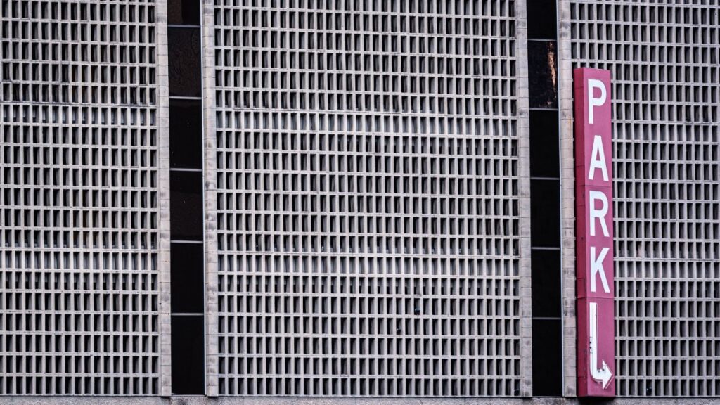 Close-up of urban parking garage facade with red sign in Dallas, Texas.
