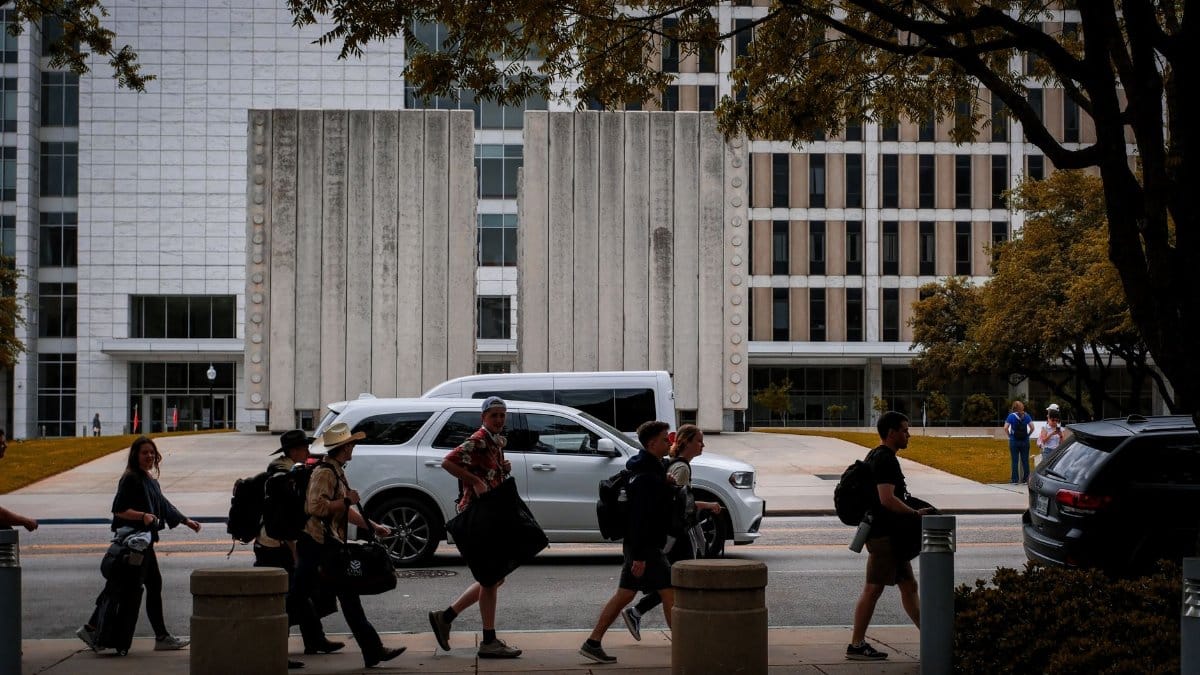 People crossing the street in Dallas in front of a modern office building on a sunny day.