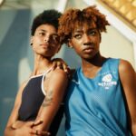 Two black women with short curly hair in sportswear pose stylishly outdoors