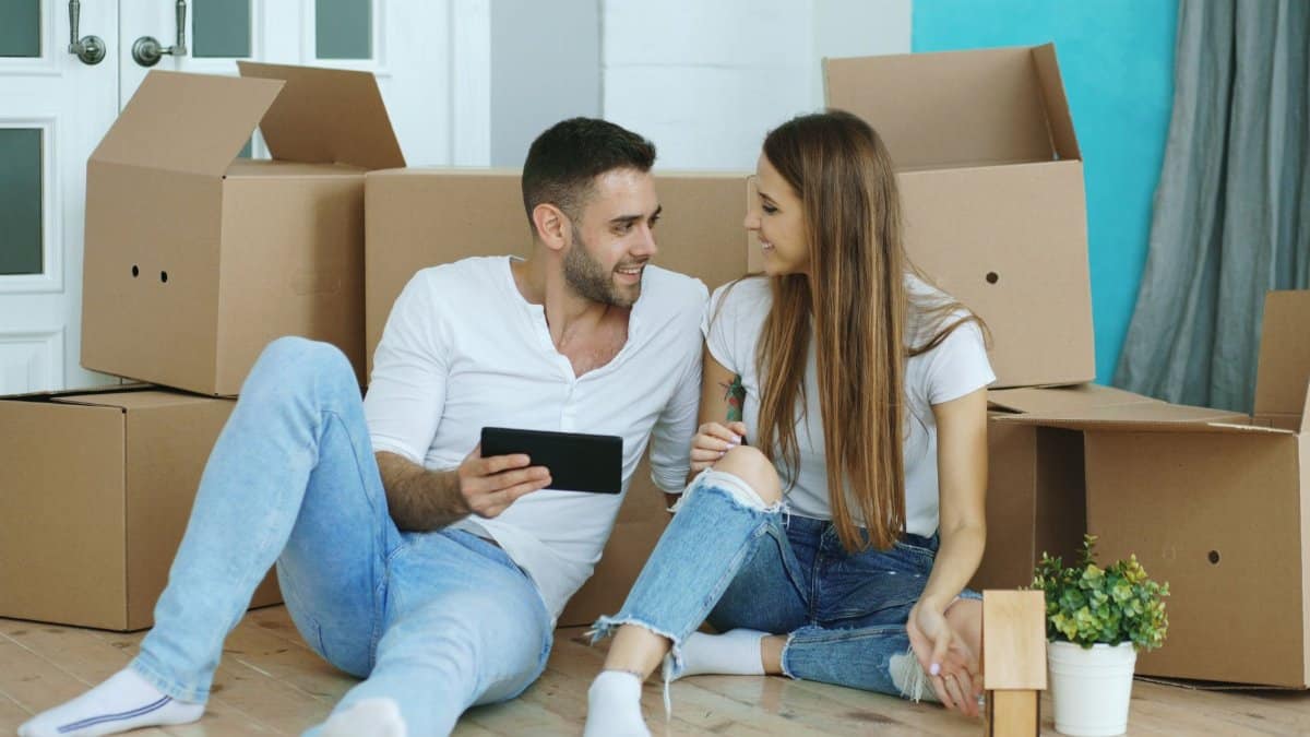 Happy couple relaxing in new home with moving boxes, enjoying their time together.