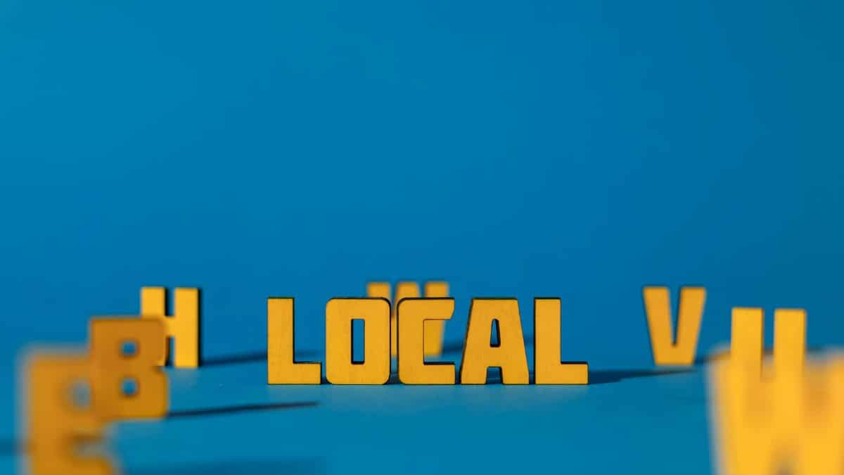 Abstract image featuring yellow wooden letters spelling 'LOCAL' on a blue background, offering ample copy space.