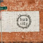 Urban street art featuring 'Hub City' mural on a red brick wall in Deep Ellum, Dallas, Texas.