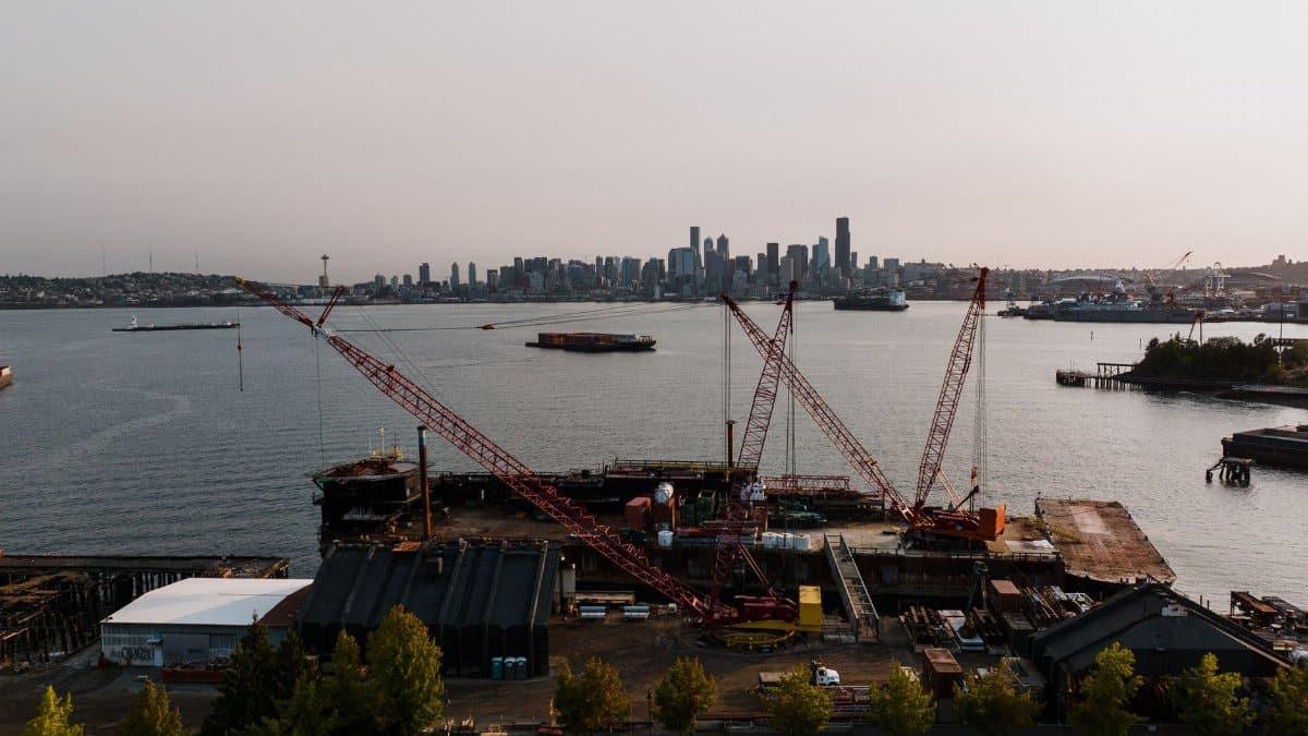 Aerial view of Seattle harbor with cranes and city skyline at day.