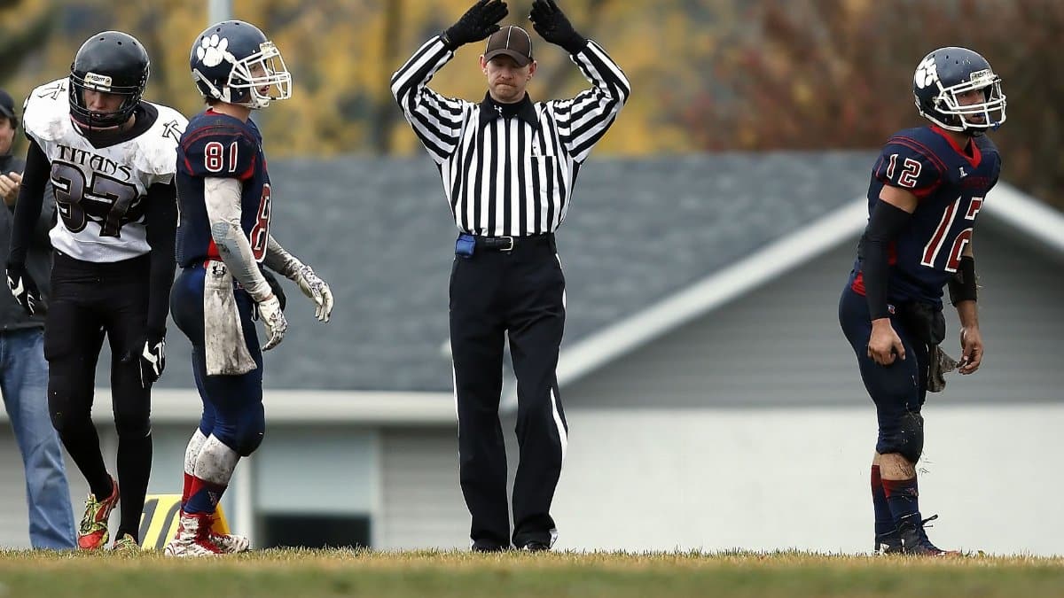 Referee calls timeout during intense high school football game outdoors.