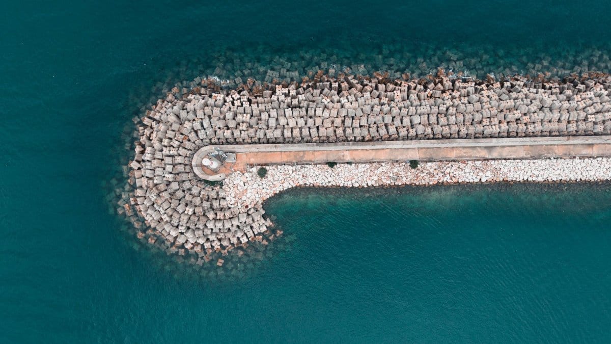 Aerial shot of a breakwater in Antalya, Turkey, surrounded by a tranquil turquoise sea.