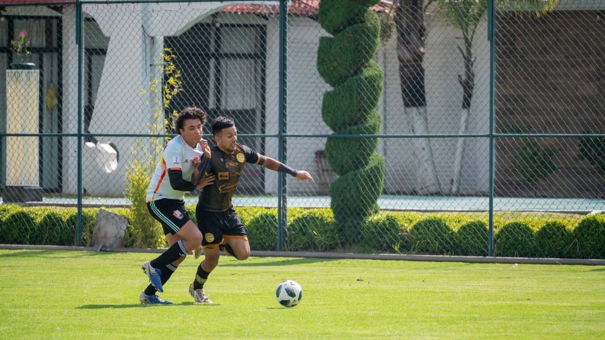 Two athletes compete fiercely in a soccer match on a sunny day in Texcoco, Mexico.