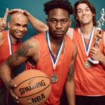 Three basketball players celebrating victory with trophies and medals, showcasing teamwork and accomplishment.