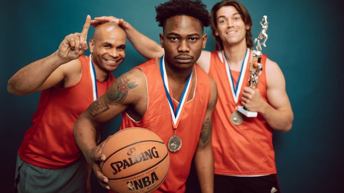 Three basketball players celebrating victory with trophies and medals, showcasing teamwork and accomplishment.