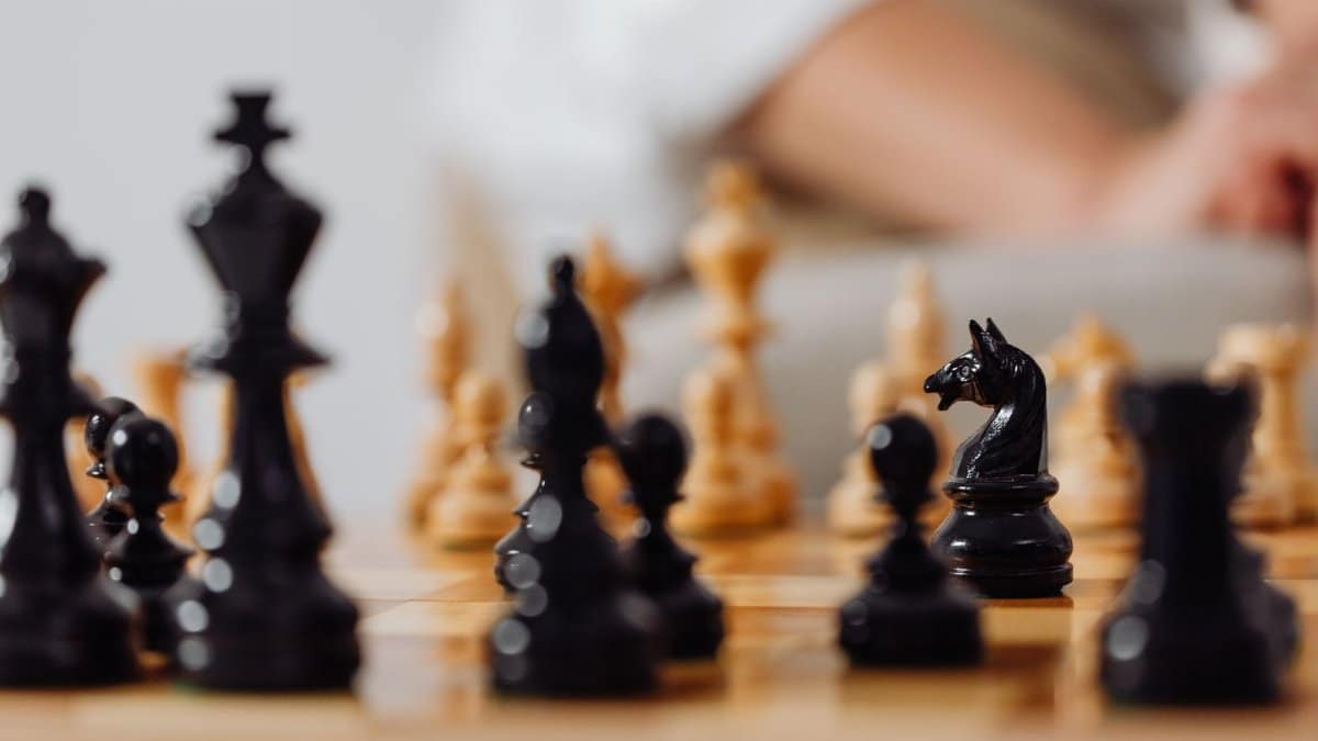 Detailed view of wooden chessboard with focused black chess pieces, creating a strategic atmosphere.