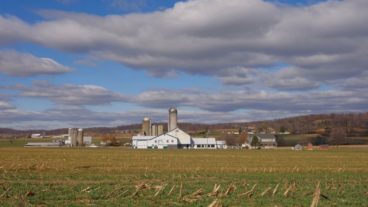 A picturesque rural scene of a farm with silos under a cloudy sky in Pennsylvania.