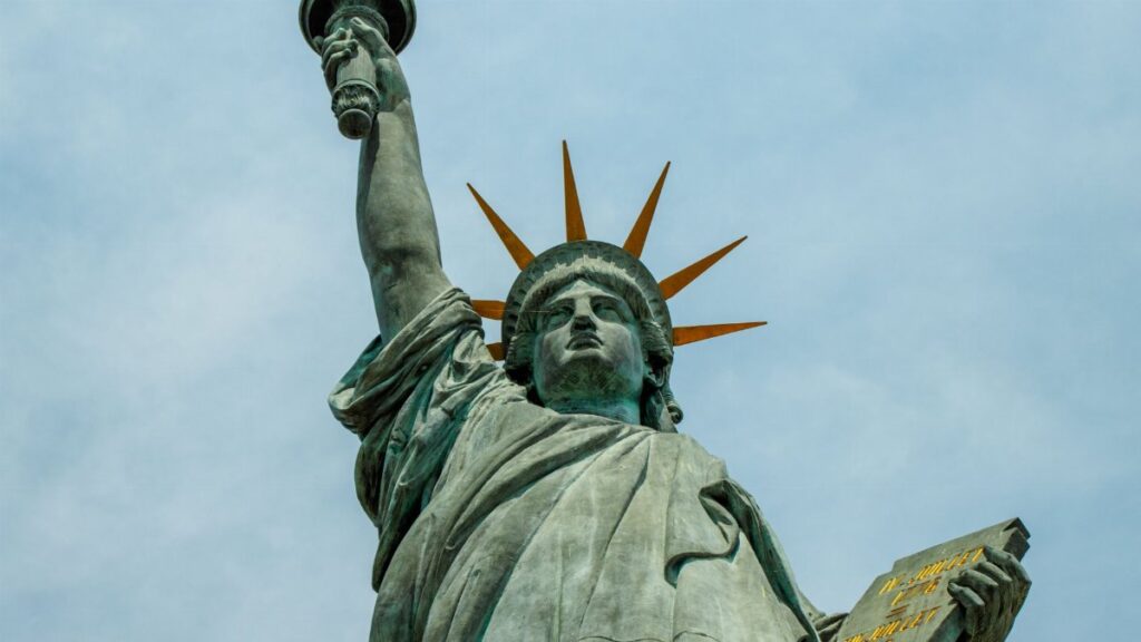 Dramatic perspective of the iconic Statue of Liberty with a cloudy sky backdrop.