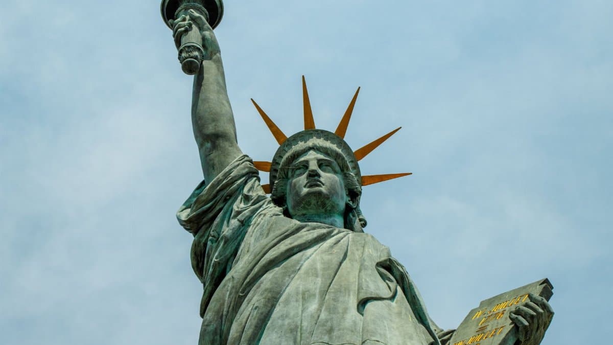 Dramatic perspective of the iconic Statue of Liberty with a cloudy sky backdrop.