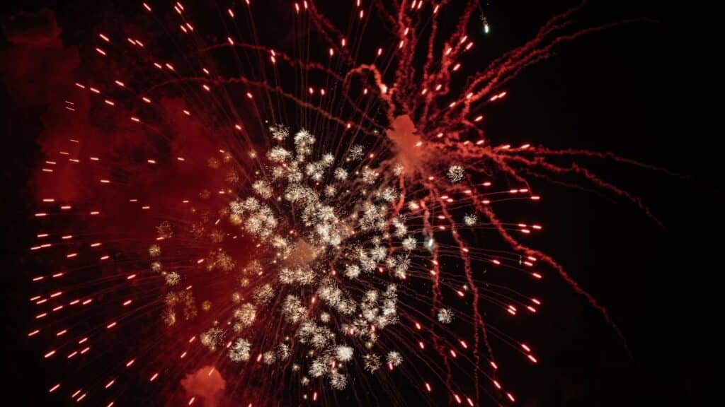 A dazzling display of red fireworks lights up the night sky, perfect for celebrations and holidays.