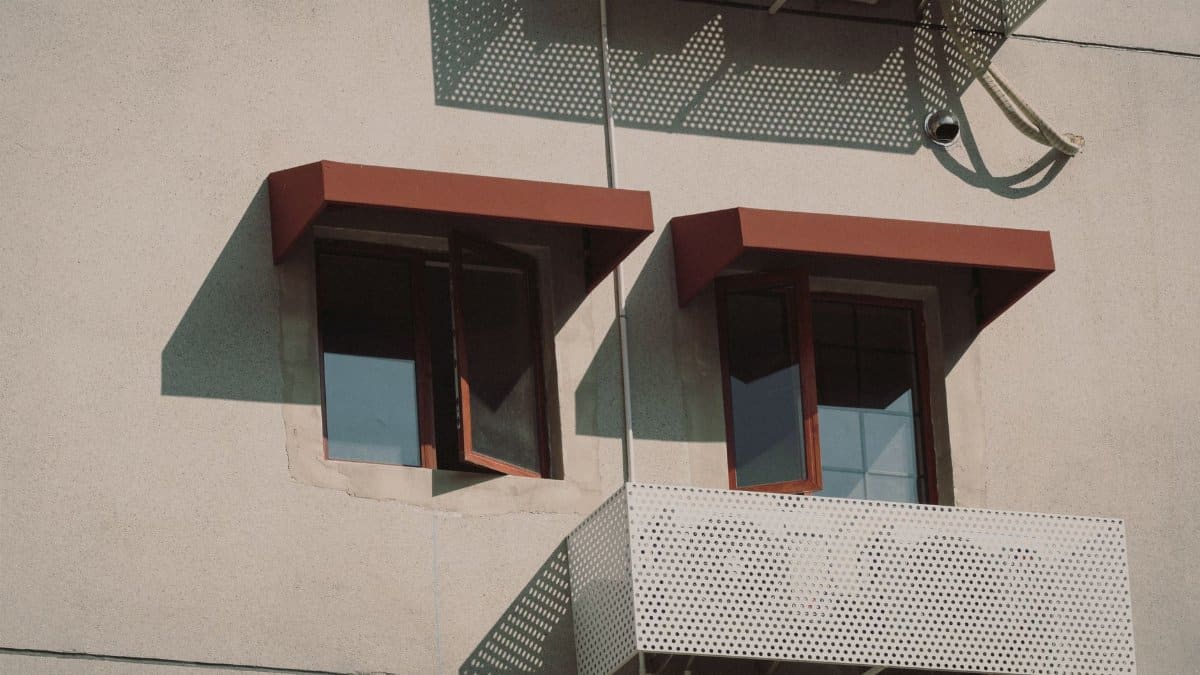 Close-up of a building facade with modern windows casting geometric shadows, emphasizing architectural design.