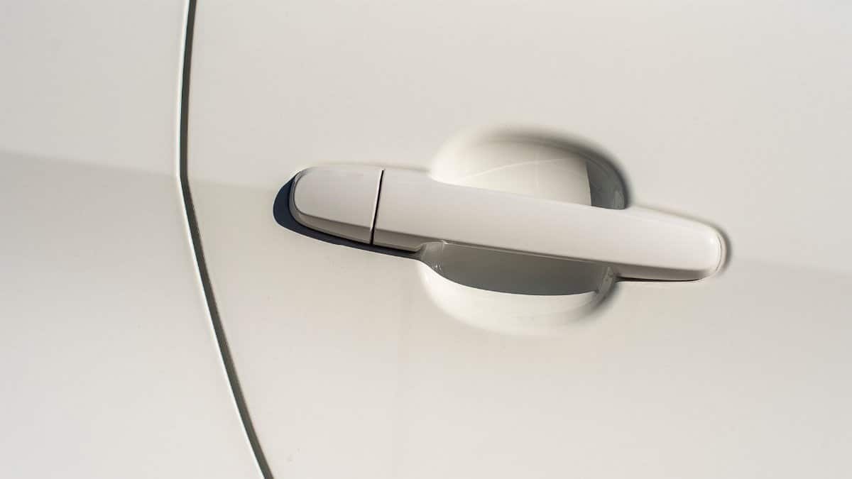 Minimalist close-up view of a sleek white car door handle highlighting the modern design.