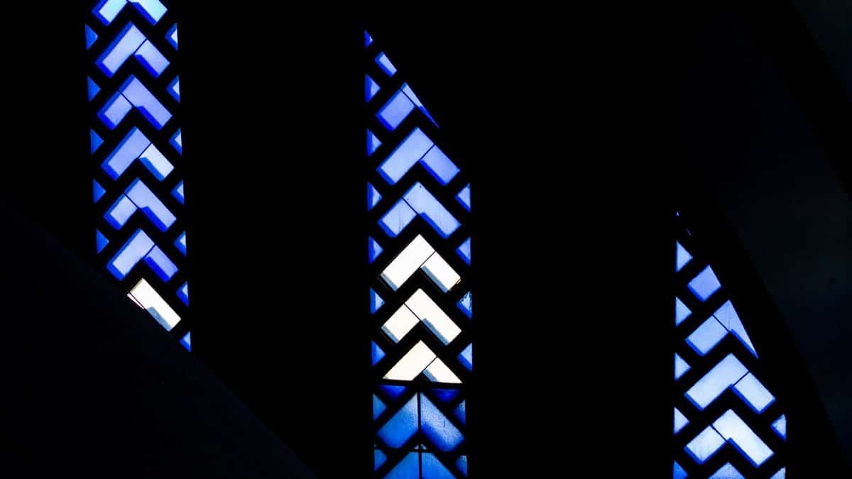 Dark abstract design featuring blue stained glass patterns with geometric shapes.