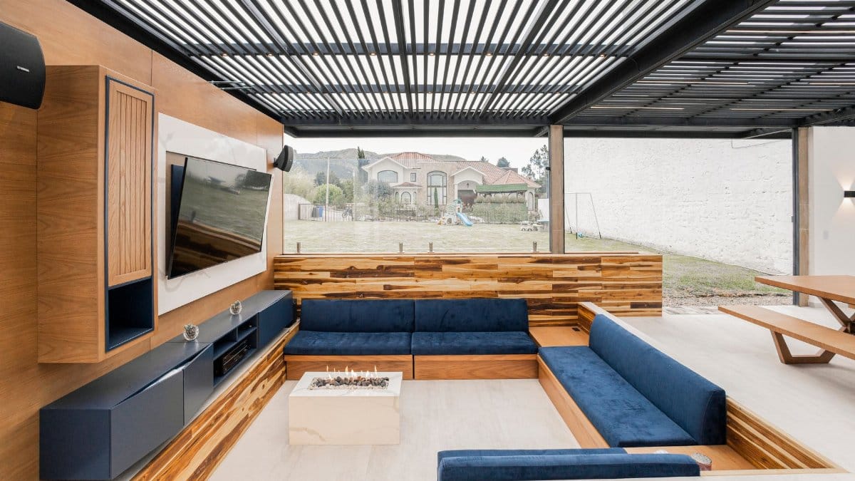 Contemporary outdoor living room featuring a cozy blue sofa, wooden accents, and glass wall.