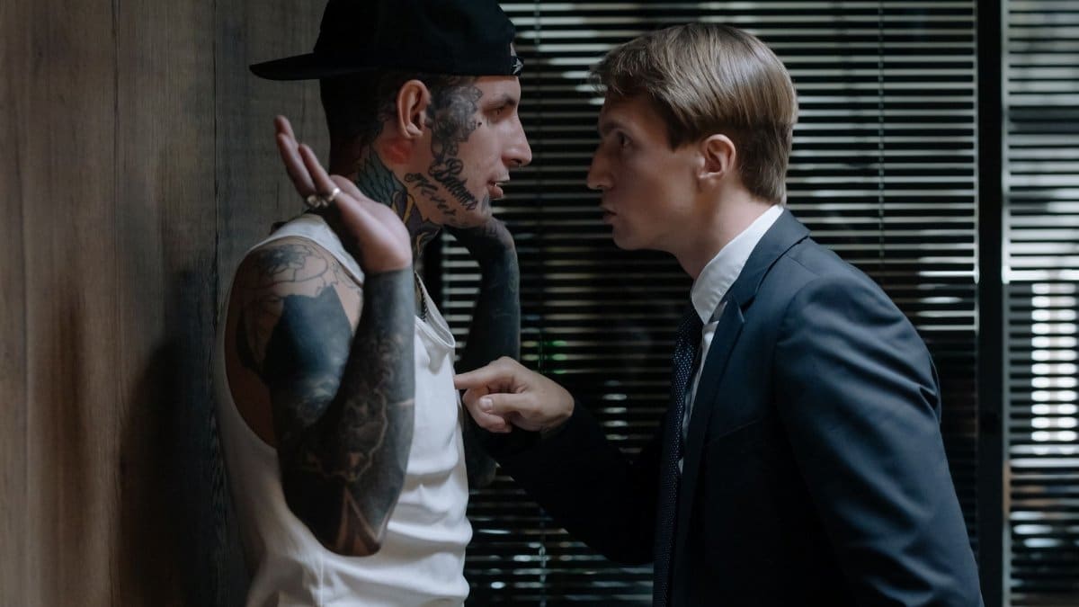 A tense indoor scene depicting an intense interrogation confrontation between two men.