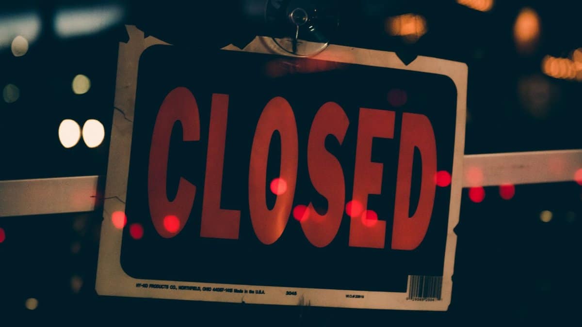 Moody image of a closed sign with bokeh lights, conveying nighttime closure.
