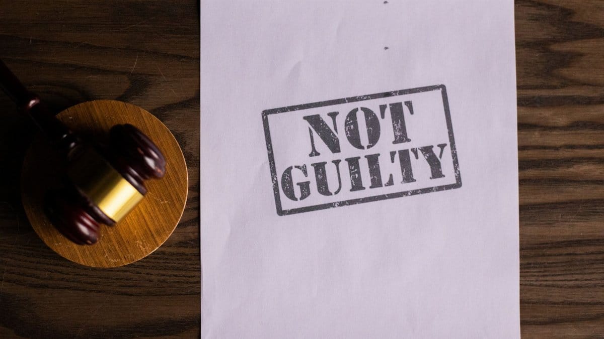 A courtroom document labeled 'Not Guilty' beside a gavel symbolizes justice.