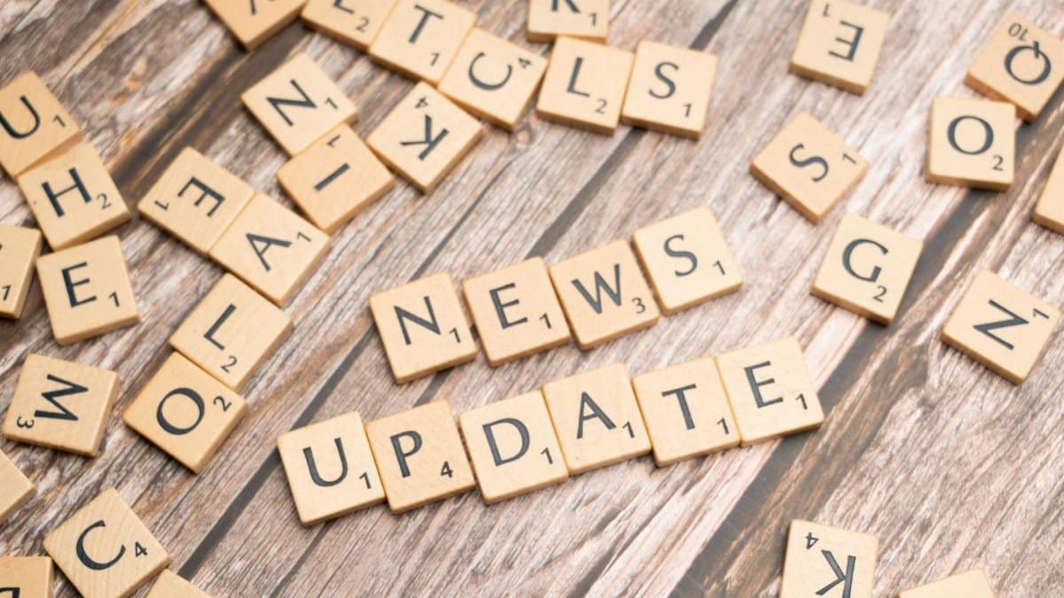 Scrabble tiles spelling 'News Update' on a wooden background, ideal for media and communication concepts.