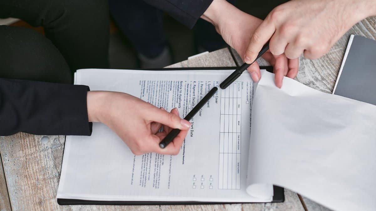 Close-up of business hands finalizing agreement with pen on documents.