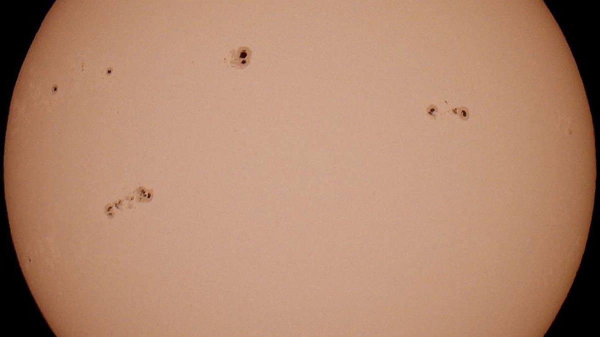 Close-up of the sun with visible sunspots, showcasing solar surface details.