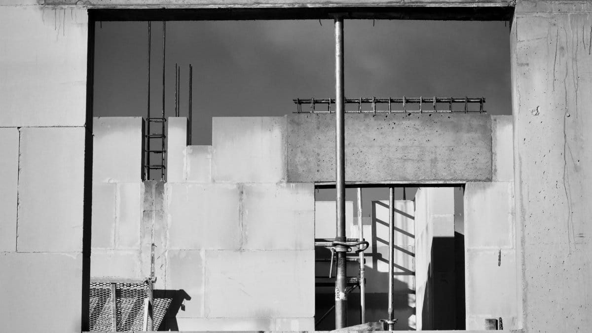 Monochrome image showcasing a construction site in progress, featuring scaffolding and concrete walls.