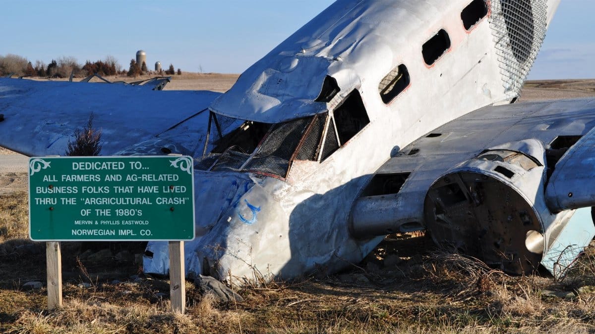 A wrecked airplane amid an open farmland, symbolizing the agricultural crash of the 1980s.