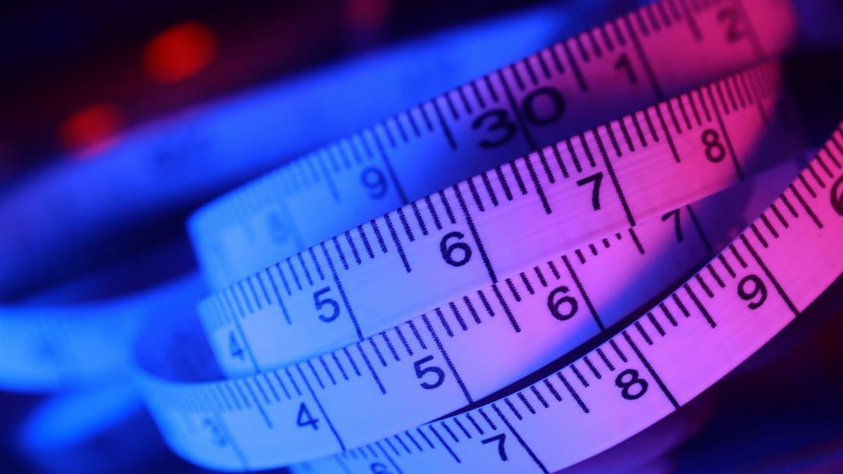 Abstract close-up of a measuring tape in vibrant blue and pink lighting.
