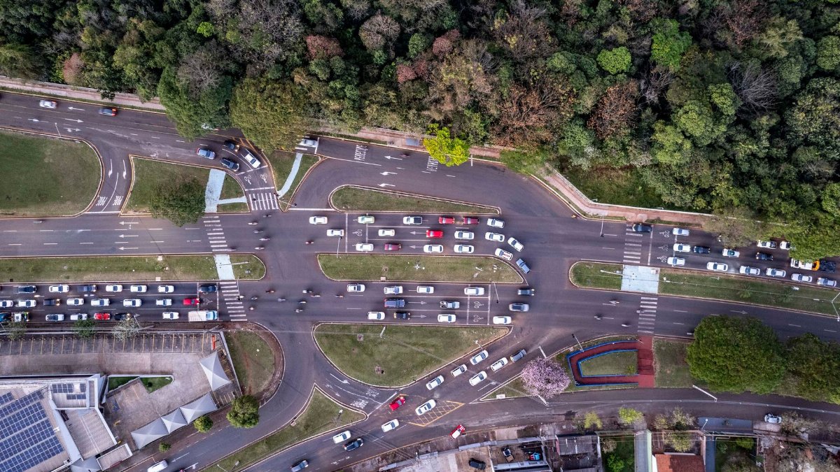 A drone shot capturing busy traffic at an intersection in Londrina, Brazil surrounded by lush greenery.