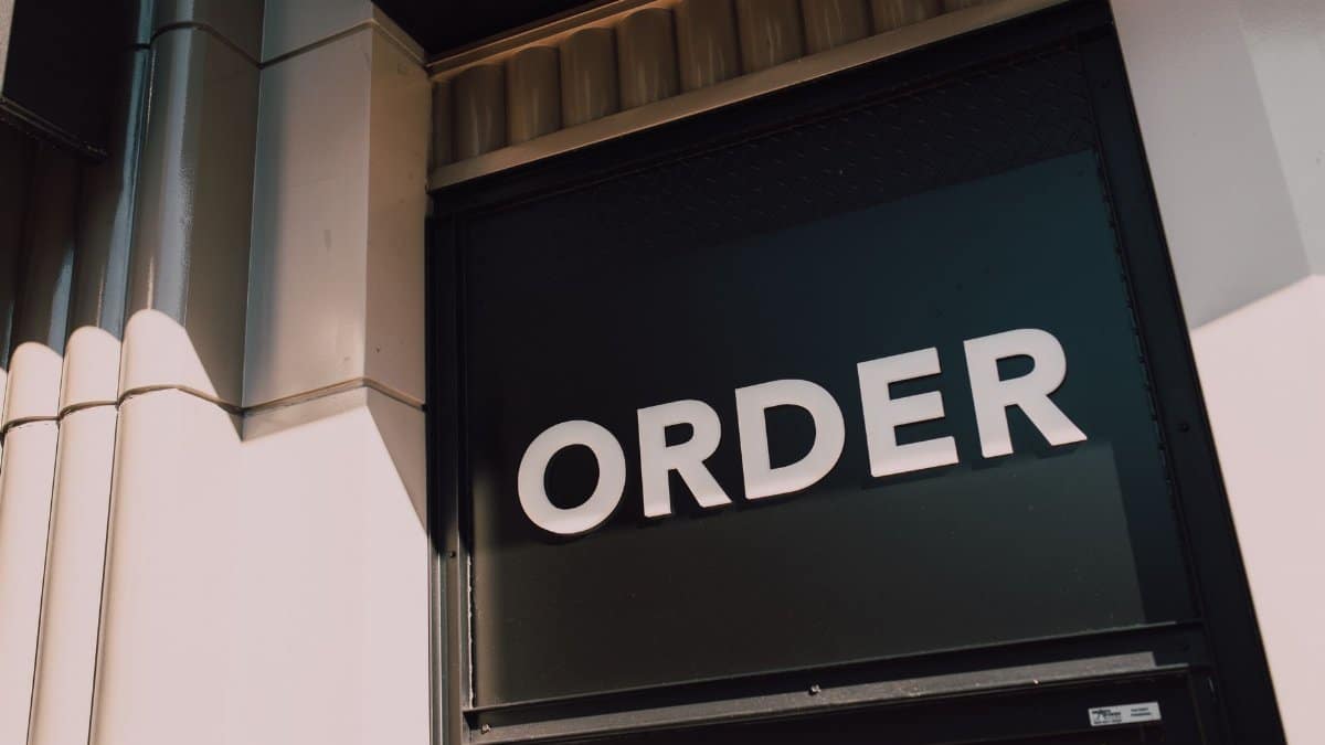 A sunlit view of a modern storefront with prominent 'Order' signage, highlighting a streamlined design.