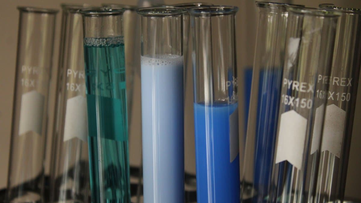 Close-up of colorful chemical solutions in glass test tubes in a laboratory setting.