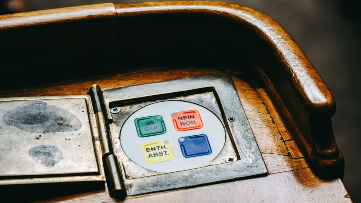 Wooden voting panel with multilingual buttons in Bern's Parliament, Switzerland.