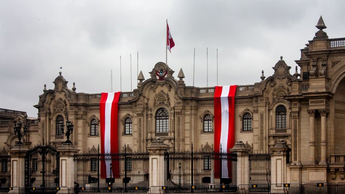 The Presidential Palace in Lima, Peru, with vibrant red and white flags displayed on the facade.