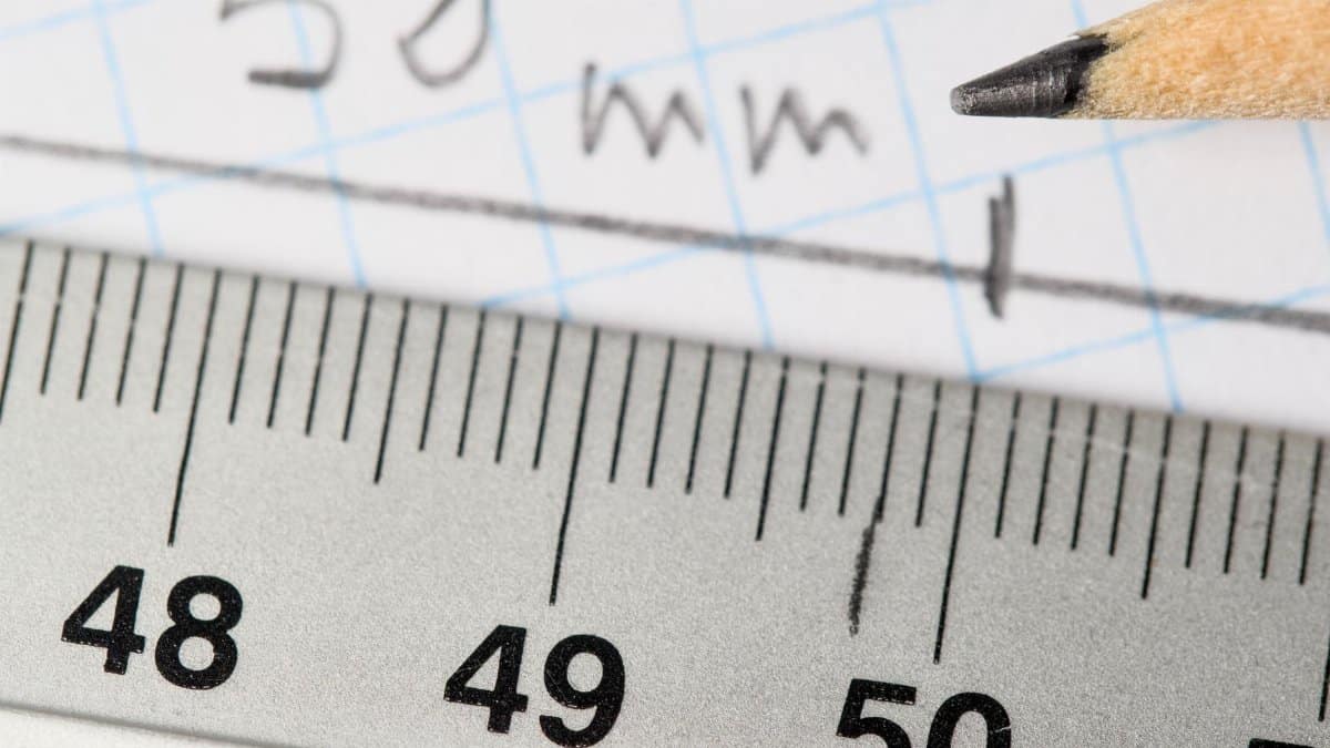 Detailed image of a ruler and pencil marking 50mm on graph paper.
