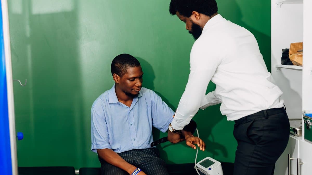 A doctor performs a blood pressure check in a Lagos clinic, emphasizing healthcare.